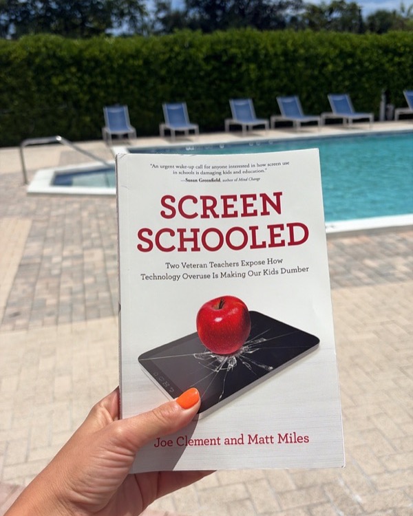 Holding a copy of the book Screen Schooled by Joe Clement and Matt Miles